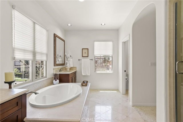 bathroom with baseboards, recessed lighting, a bath, and vanity