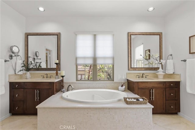 bathroom featuring a bath, two vanities, and a sink