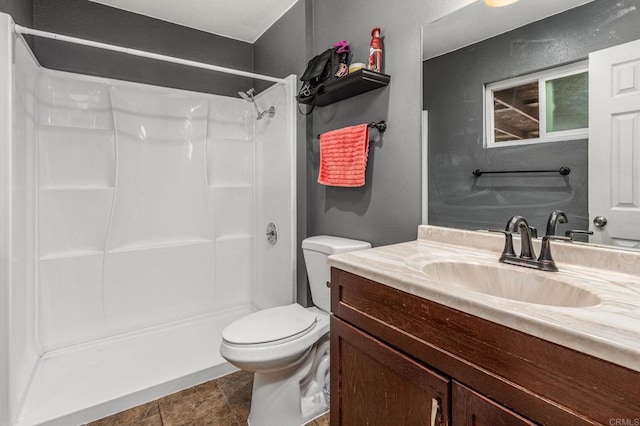bathroom with toilet, stone finish floor, a shower, and vanity