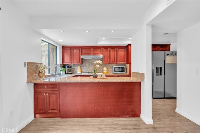 kitchen featuring stainless steel appliances, extractor fan, a sink, and light wood finished floors