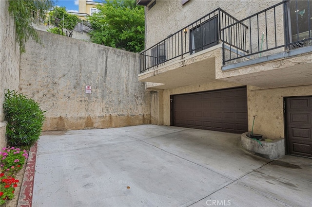view of home's exterior featuring a garage, stucco siding, and a balcony