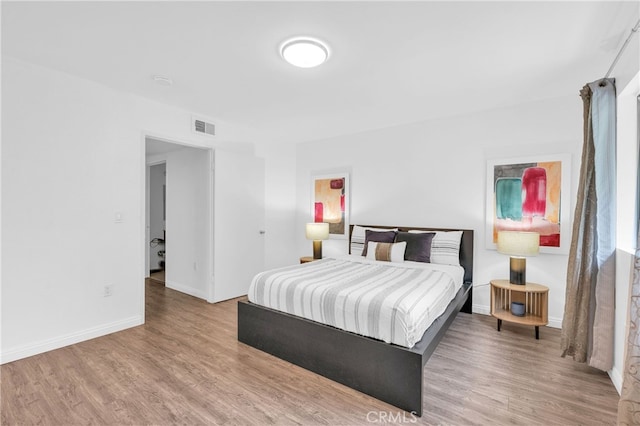 bedroom with visible vents, baseboards, and wood finished floors