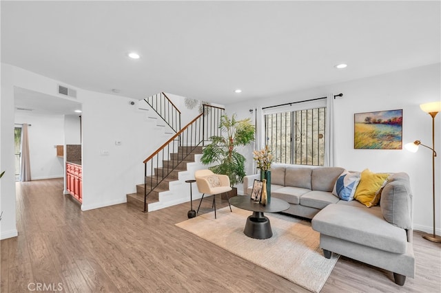 living room with stairs, recessed lighting, light wood-style flooring, and visible vents