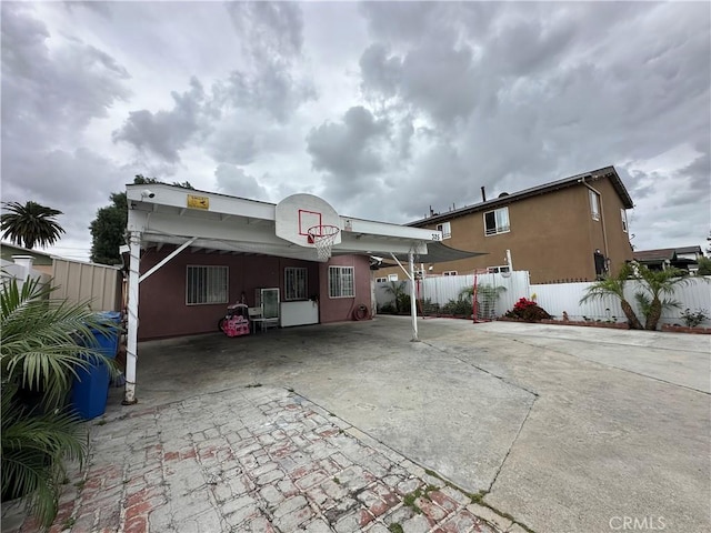 323 E 107th St, Los Angeles, CA 90003 - rear view of house featuring fence, driveway, and stucco siding