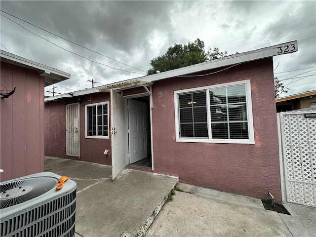 323 E 107th St, Los Angeles, CA 90003 - property entrance with stucco siding, a patio, and central AC unit