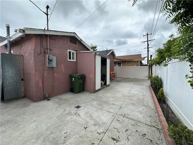 323 E 107th St, Los Angeles, CA 90003 - view of side of home featuring a patio area, a fenced backyard, an outdoor structure, and stucco siding