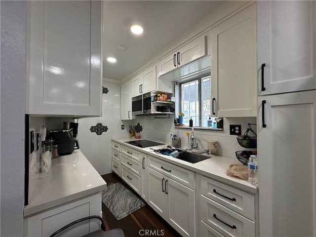 323 E 107th St, Los Angeles, CA 90003 - kitchen with white cabinets, black electric cooktop, light countertops, a sink, and stainless steel microwave