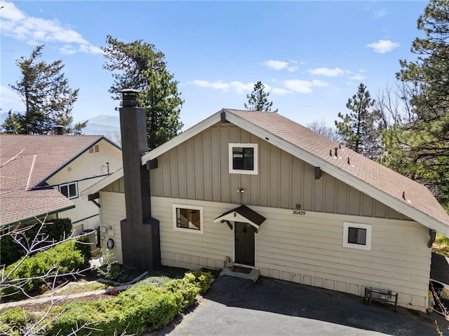 view of front of home featuring board and batten siding, aphalt driveway, roof with shingles, a mountain view, and a garage