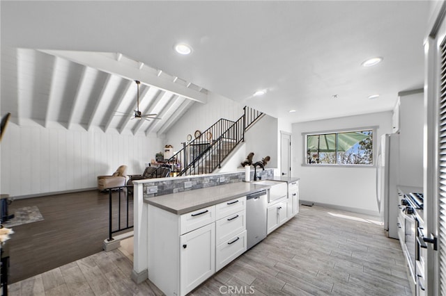 kitchen featuring white cabinets, stainless steel appliances, a sink, light wood-type flooring, and baseboards