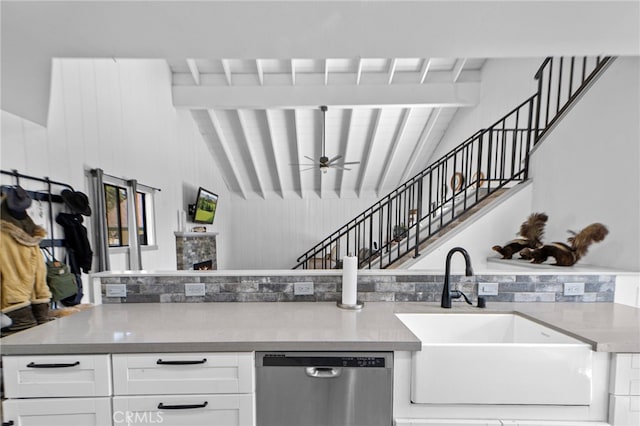 kitchen featuring lofted ceiling with beams, stainless steel dishwasher, white cabinets, ceiling fan, and a sink