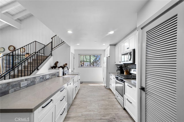 kitchen with white cabinetry, light wood-style flooring, stainless steel appliances, baseboards, and recessed lighting