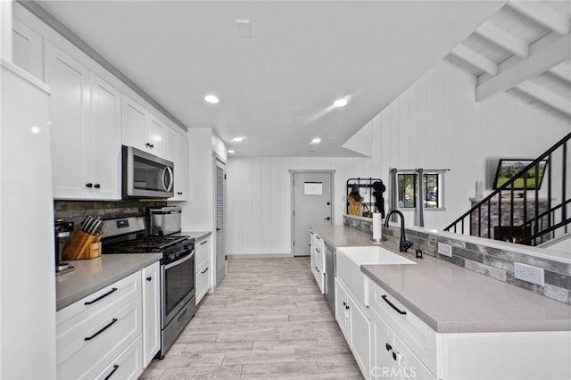 kitchen with white cabinets, stainless steel appliances, a sink, tasteful backsplash, and lofted ceiling