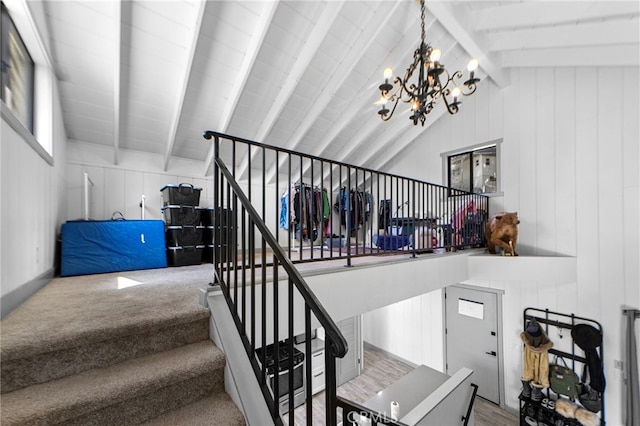 staircase with vaulted ceiling with beams, wooden walls, and a chandelier
