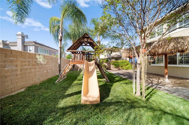 view of play area with fence, a patio area, and a lawn