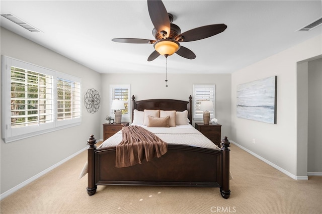 bedroom with baseboards, visible vents, and light carpet