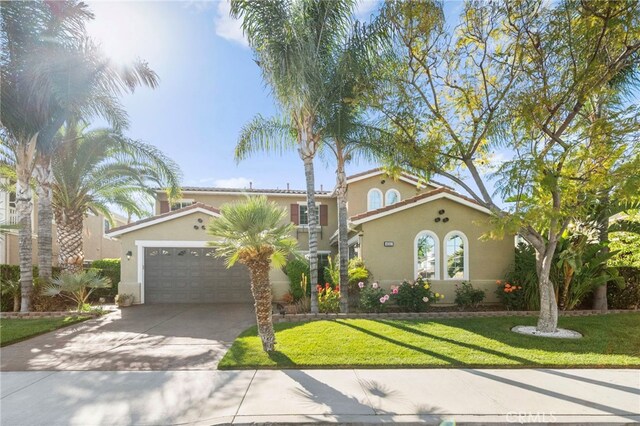 mediterranean / spanish home with stucco siding, concrete driveway, a front yard, and a garage