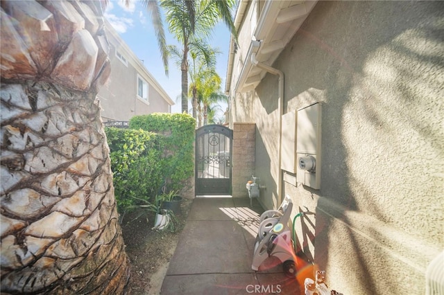 view of side of property with stucco siding and a gate