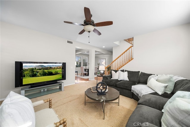 carpeted living room featuring baseboards, visible vents, ceiling fan, and stairs