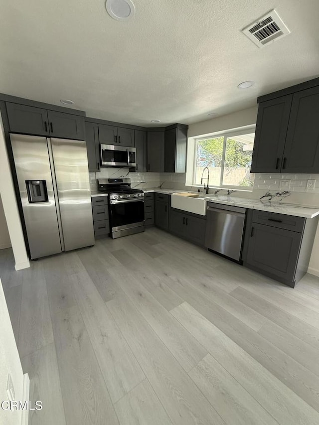 kitchen featuring visible vents, appliances with stainless steel finishes, light wood-style flooring, and a sink