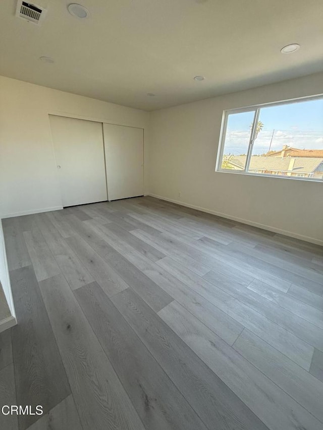 unfurnished bedroom with recessed lighting, a closet, visible vents, baseboards, and wood finished floors