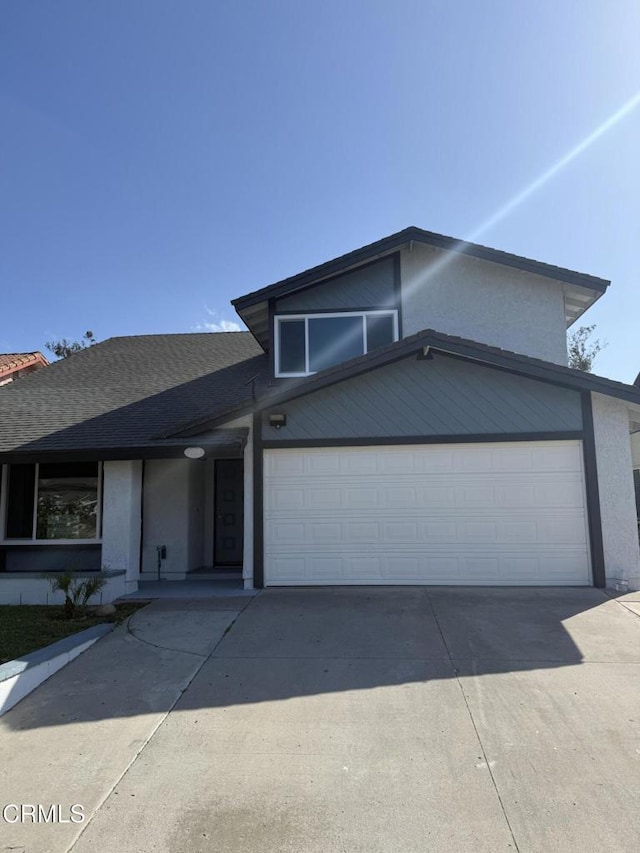 view of front of house with stucco siding, concrete driveway, a shingled roof, and an attached garage