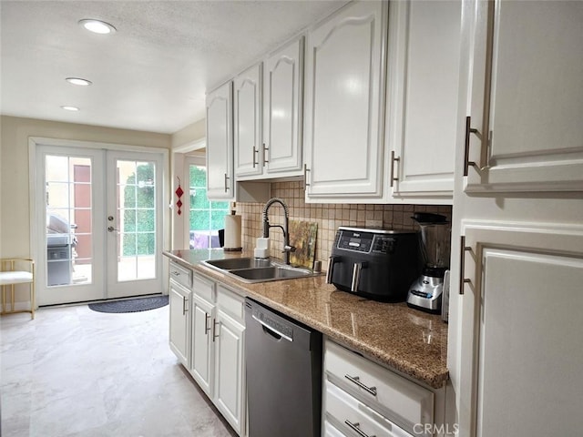 kitchen with stainless steel dishwasher, french doors, a sink, and white cabinets