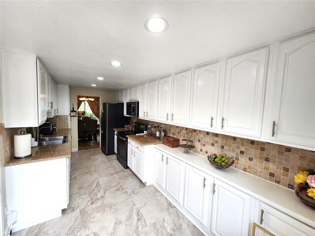 kitchen with freestanding refrigerator, electric range, white cabinets, a sink, and backsplash