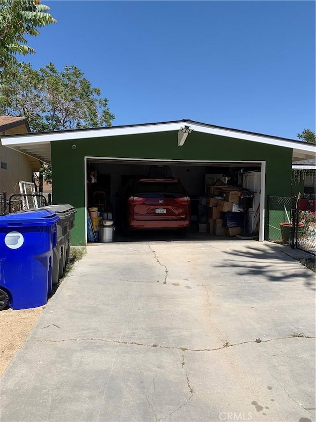 garage featuring concrete driveway and fence