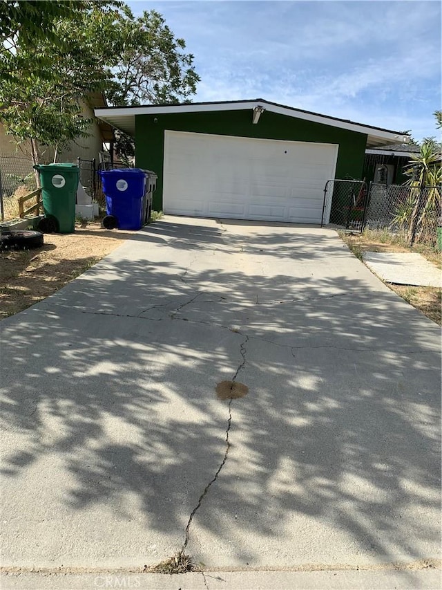 view of side of property with a garage, fence, stucco siding, and driveway