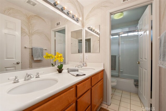 bathroom featuring toilet, a sink, tile patterned floors, and visible vents