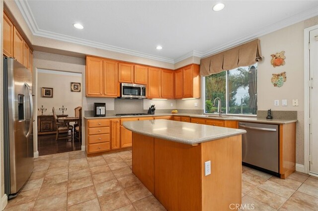 kitchen with ornamental molding, a center island, a sink, and stainless steel appliances