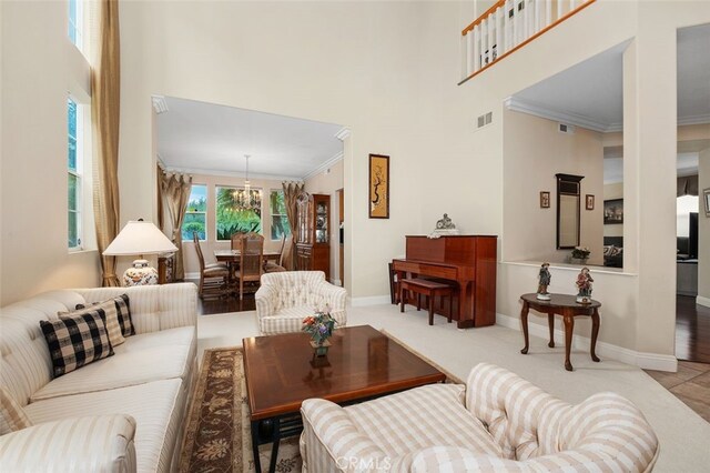 living area featuring a towering ceiling, visible vents, ornamental molding, and baseboards