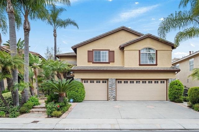 traditional-style house with stucco siding, concrete driveway, stone siding, and a garage