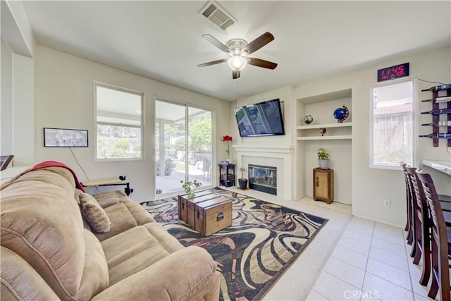 32851 Naples Ct, Temecula, CA 92592 - living room with a fireplace, built in features, tile patterned floors, a ceiling fan, and visible vents