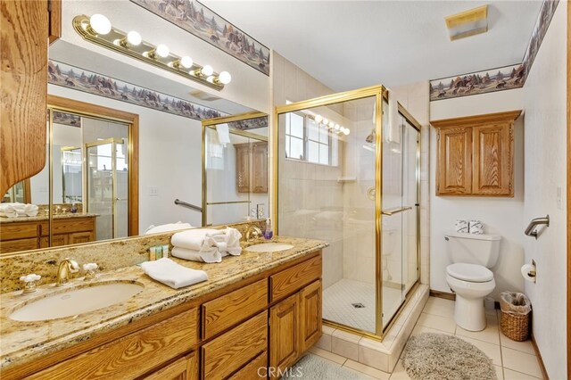 full bath with a sink, a shower stall, double vanity, and toilet