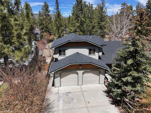 view of front facade with stucco siding, a shingled roof, and concrete driveway