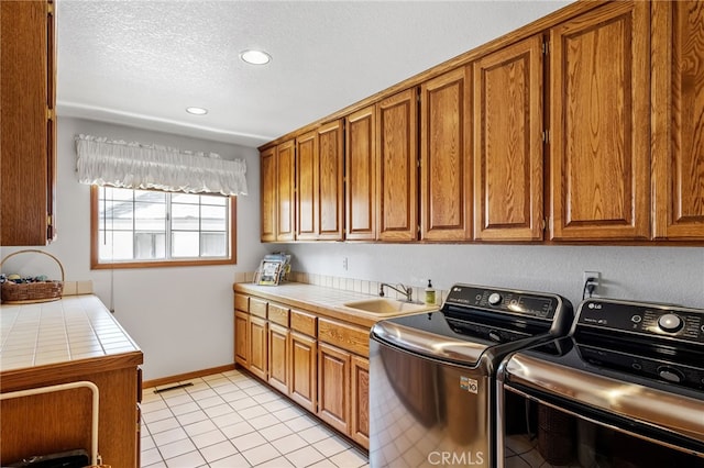 laundry room featuring recessed lighting, light tile patterned floors, a sink, washing machine and clothes dryer, and cabinet space