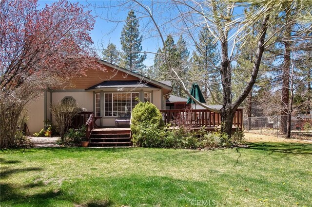 back of house featuring stucco siding, a lawn, fence, and a deck