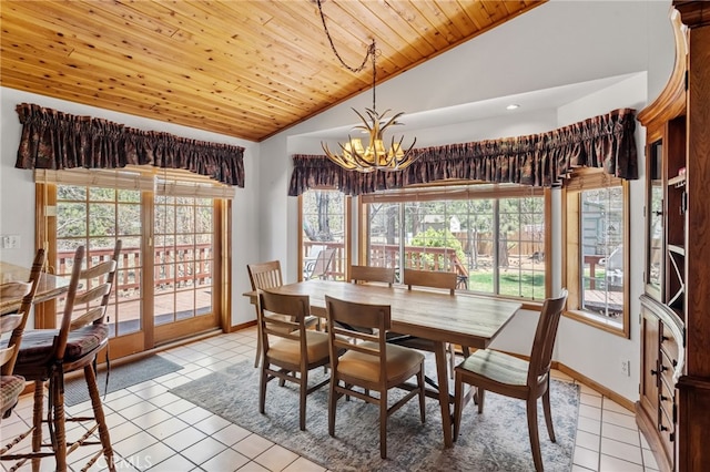 dining space featuring an inviting chandelier, vaulted ceiling, baseboards, and light tile patterned floors