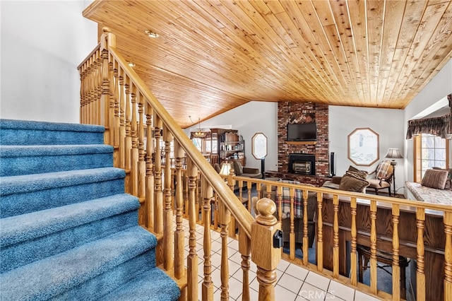 staircase with vaulted ceiling, a brick fireplace, tile patterned flooring, and wooden ceiling