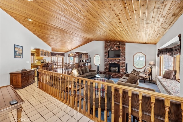living area featuring vaulted ceiling, plenty of natural light, light tile patterned floors, wooden ceiling, and a brick fireplace