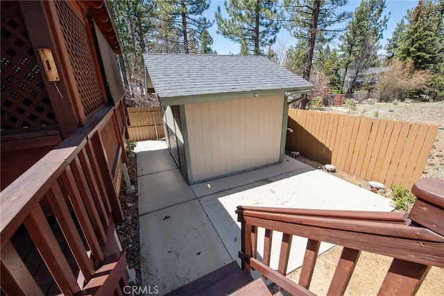 view of patio featuring fence, a storage unit, and an outbuilding