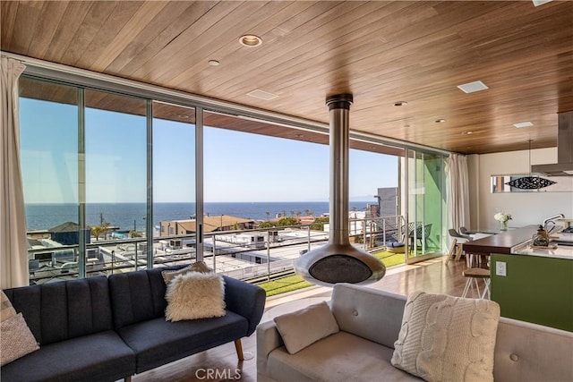 living area with wooden ceiling, a water view, and expansive windows
