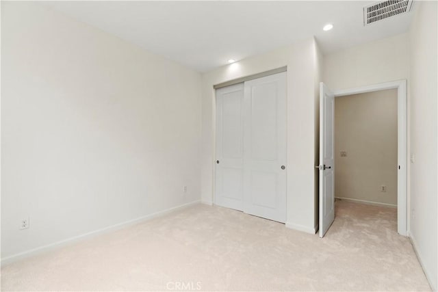 unfurnished bedroom featuring visible vents, a closet, baseboards, recessed lighting, and light carpet
