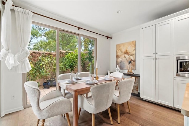 dining room with light wood-style floors and ornamental molding