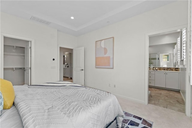 bedroom featuring a closet, light carpet, ensuite bathroom, baseboards, and visible vents