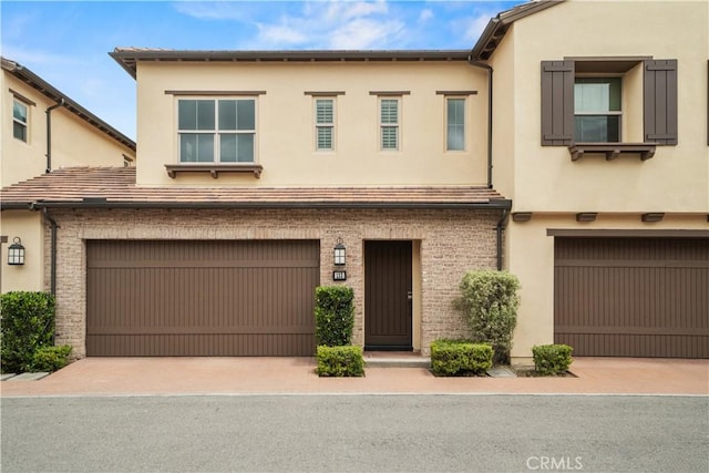 multi unit property featuring a garage, stucco siding, and decorative driveway