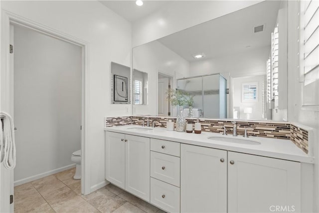full bathroom featuring toilet, decorative backsplash, a shower stall, and a sink
