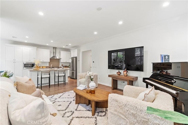 living area with light wood finished floors, recessed lighting, ornamental molding, and baseboards