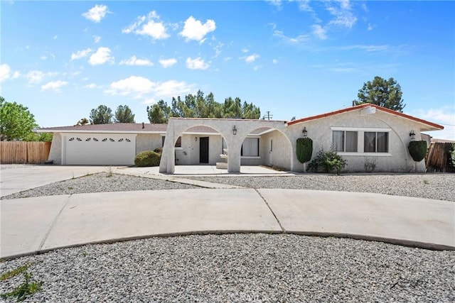 view of front of property with an attached garage, driveway, stucco siding, and fence